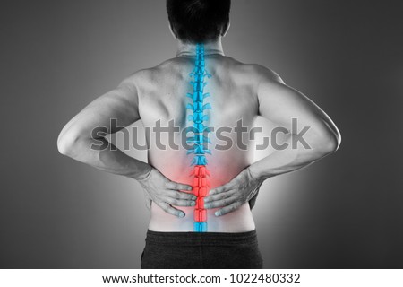 Pain in the spine, a man with backache, injury in the lower back, black and white photo with highlighted skeleton