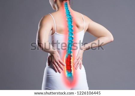 Pain in the spine, woman with backache on gray background, back injury, photo with highlighted skeleton