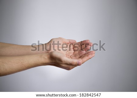 Male hands on a gray background. Empty outstretched palm. Copy space