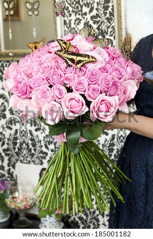 Bouquet of pink roses with live butterflies in female hands