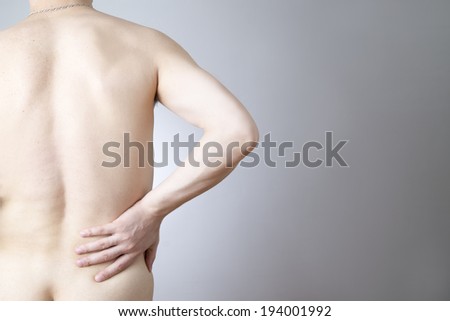 Pain in the lower back in men on gray background