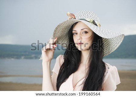 Portrait of a beautiful young woman in hat on the beach in summer