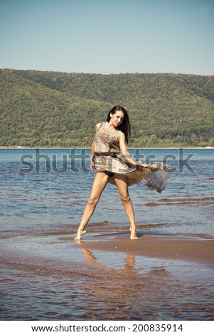 Beautiful young woman in a dress on beach. Dress  waving in the wind