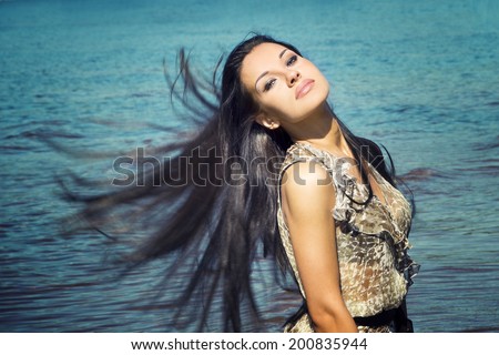 Portrait of a beautiful young woman in summer. Black long hair waving in the wind. Girl face closeup.
