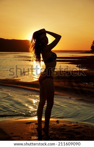 Beautiful woman in bikini on sunset background. Slim girl posing in a swimsuit. Female silhouette