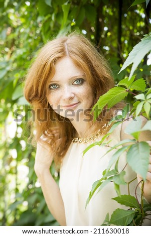 Portrait of redhead girl with blue eyes on nature. Face of young woman with freckles closeup