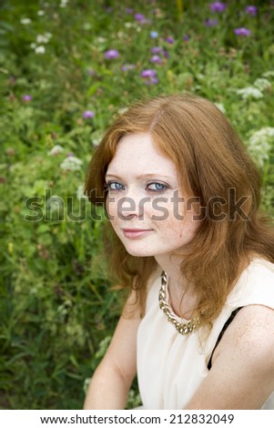 Portrait of redhead girl with blue eyes on nature. Face of young woman with freckles closeup