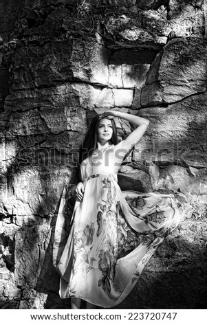 Portrait of a beautiful young woman on nature. Girl in a long dress in the rocks. Black and white photography