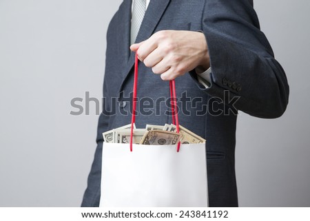 Businessman with package full of money in the hands of on gray background
