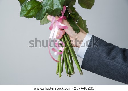 Bouquet of roses in a male hands on a gray background