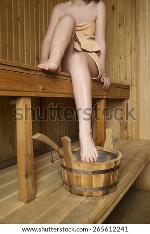 Beautiful woman in sauna, bath accessories. Wooden bucket and sticks