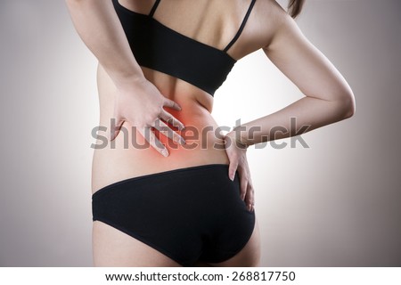 Pain in back of women on gray background. Caring for the female body. Red dot