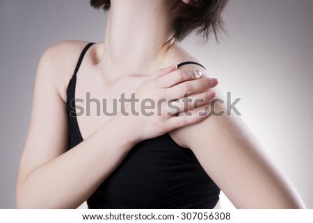 Woman with pain in shoulder. Pain in the  human body on a gray background