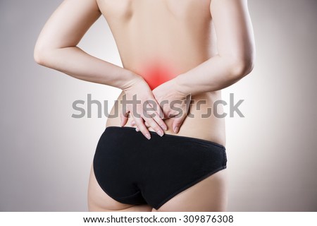 Woman with backache. Pain in the human body on a gray background with red dot
