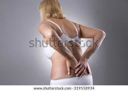 Woman with backache. Pain in the  human body on a gray background