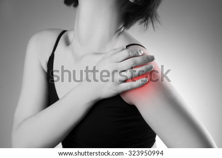 Woman with pain in shoulder. Pain in the human body. Black and white photo with red dot