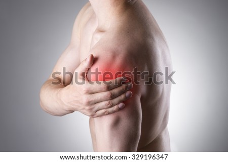 Man with pain in shoulder. Pain in the human body on a gray background with red dot