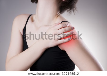 Woman with pain in shoulder. Pain in the human body on a gray background with red dot