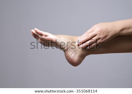 Pain in the foot. Massage of female feet on a gray background
