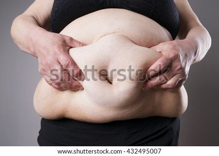 Fat female body. Fatty belly closeup on gray background