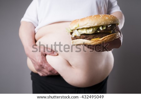 Women suffer from obesity with big hamburger in hand. Junk food concept on a gray background