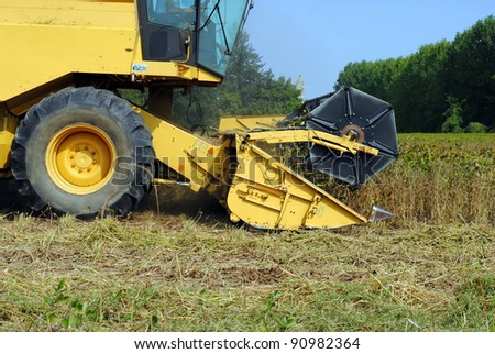 close up of a yellow combine harvester in a soy field