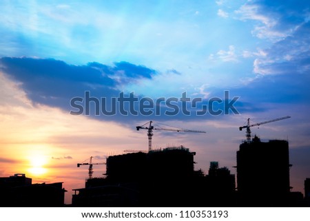 Urban scenic - Industrial construction cranes and building silhouettes at sunset