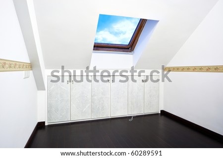 New modern attic room with a roof skylight window and wall cabinet