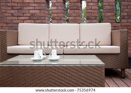 Patio with an outdoor sofa and table against the red brick wall.