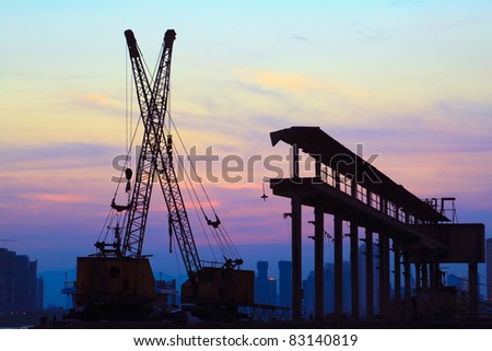 Silhouette of several cranes working at sunset in a harbor