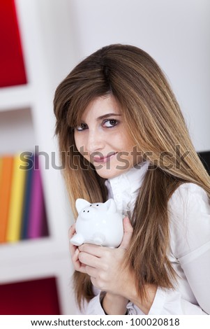 Woman holding a piggy bank at her office