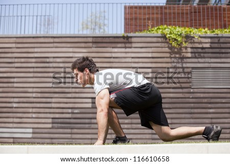 Men athlete start running next to some city wall