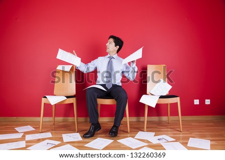 Businessman reading a document in a messy office full of papers on the floor