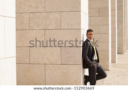 Sad businessman next to some wall looking down