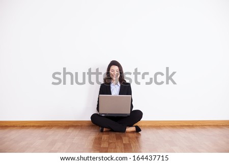 Businesswoman using her laptop sited on the floor
