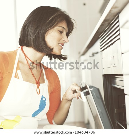 modern woman looking inside the kitchen oven
