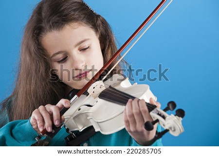 Female child playing the violin with blue background