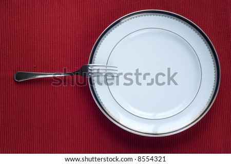 fork and porcelain plate over red (copy space in the plate)