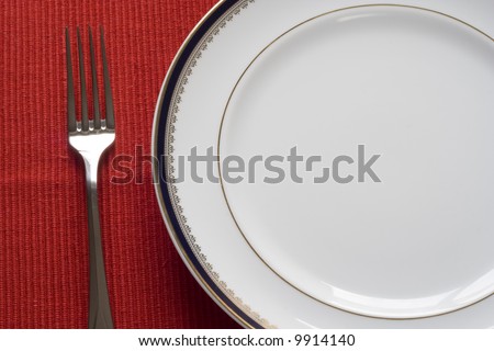 fork and porcelain plate over red (copy space in the plate)