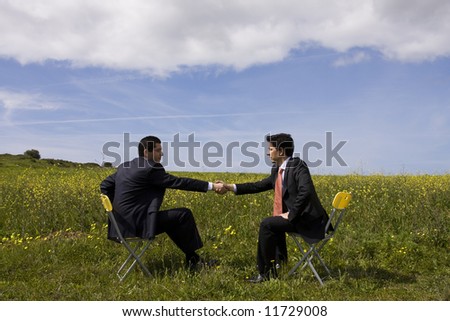 two businessman making a deal with a handshake at the field