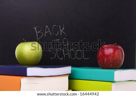 apple over a stack of books next to a chalkboard