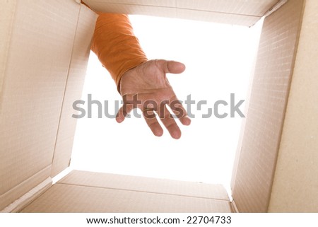 inside view of cardboard box with a hand trying to reach the content (selective focus)