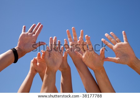 many hands raised to the blue sky (some motion blur)