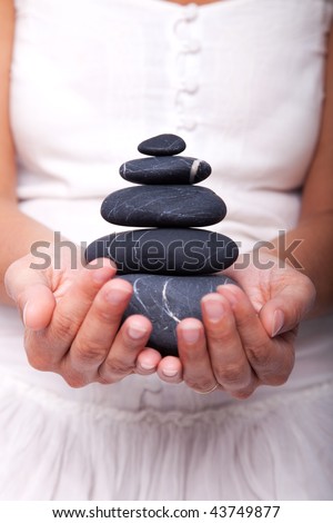 hands holding a stack of black stones (selective focus)