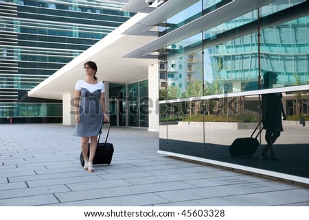 businesswoman walking with her luggage next to her office