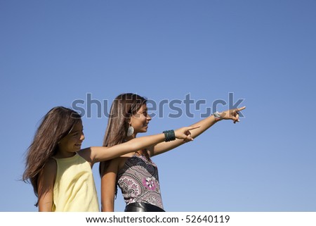 young happy sisters in outdoor pointing away