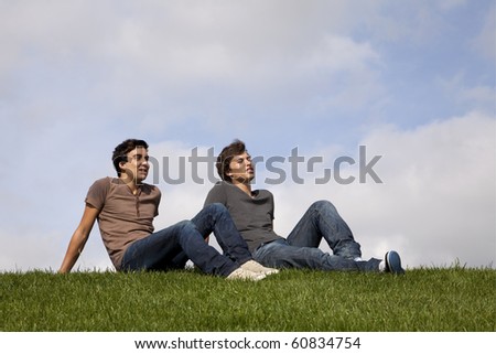 Two young men sited on the grass looking away