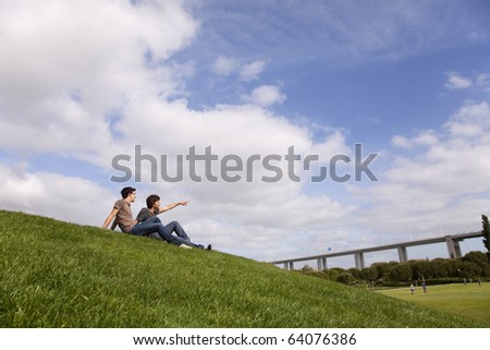 Two young men sited on the grass looking away