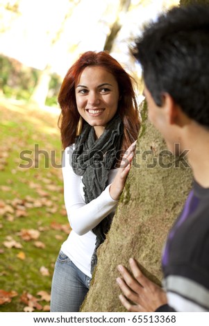 Happy times between a young couple at the park in autumn season (selective focus with shallow DOF)