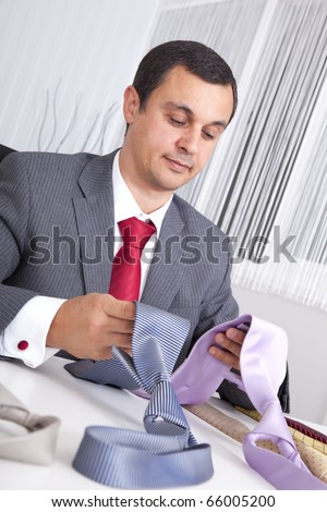 mature businessman looking to a lot of neckties, thinking what to choose